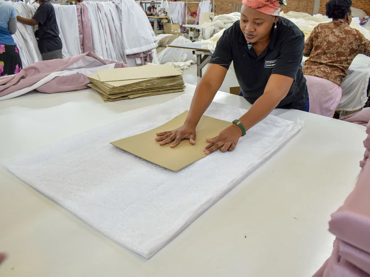 A Zaydtex quality controller checking and measuring a finished lace curtain on the factory floor