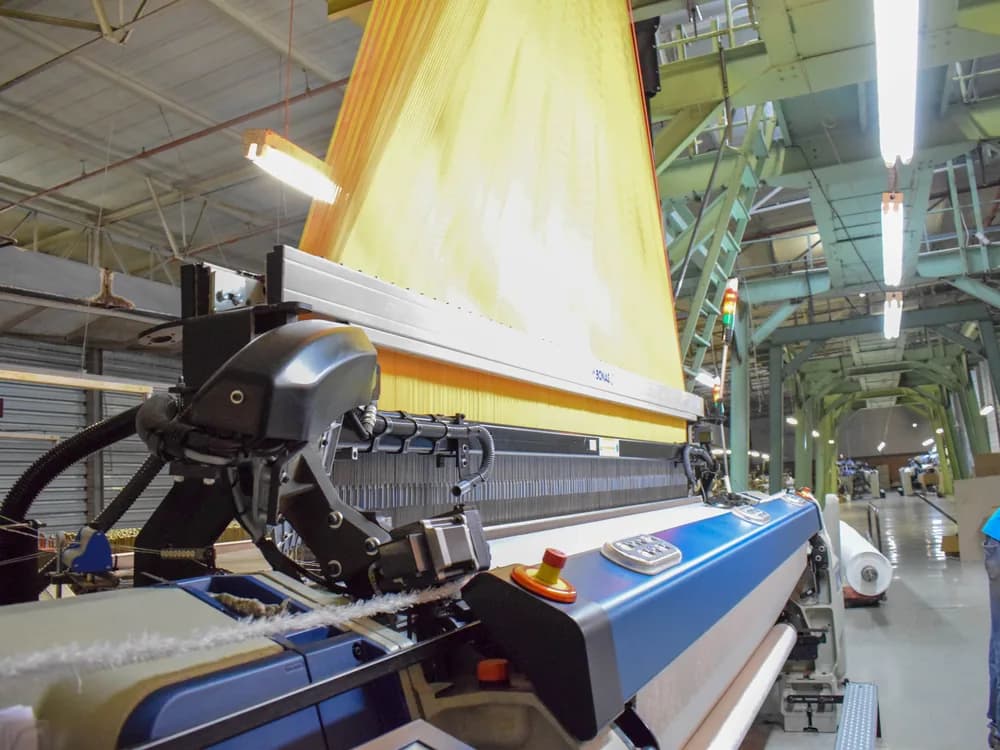 A jacquard weaving loom running a golden warp on the Korteks factory floor