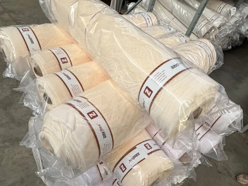 Zaydtex-branded rolls of finished fabric wrapped and racked, ready for supply